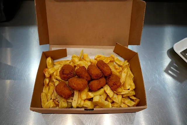 Golden southern fried chicken pieces on thick-cut chips in an open takeaway box