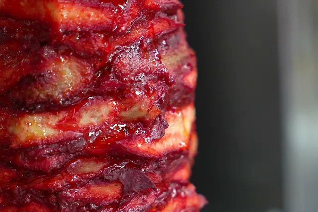 A marinated doner kebab spit turning in front of the grill