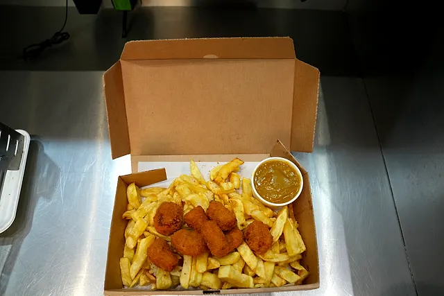A kids' box of chicken nuggets and chips with a pot of curry sauce
