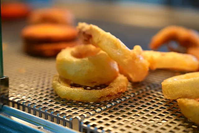 Golden battered onion rings resting under the warmer at Ideal Fish & Chips